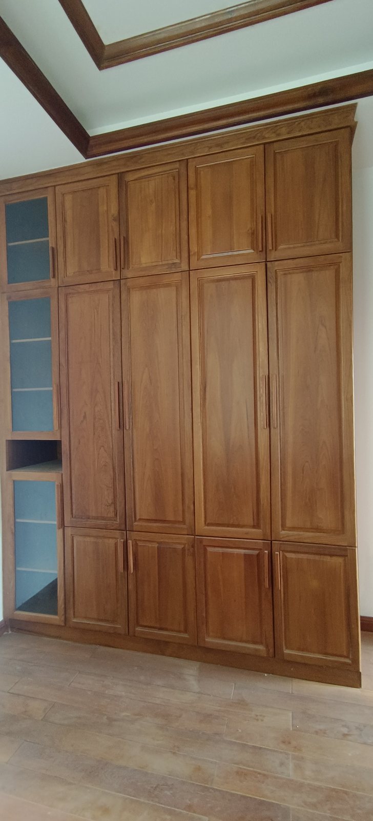 Close-up of teak wardrobe finish with brass handle and soft lighting